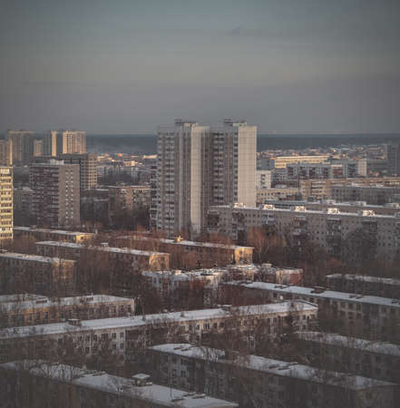 Rooftops and high residential buildings covered by snow. Winter snowy weather in the city. heating...