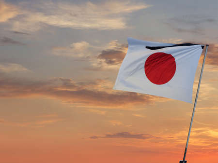 Japan flag waving against sunset orange sky, close up. Japanese flag on fieldの写真素材