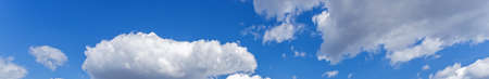 Background of light blue sky with white fluffy clouds at the bottom
