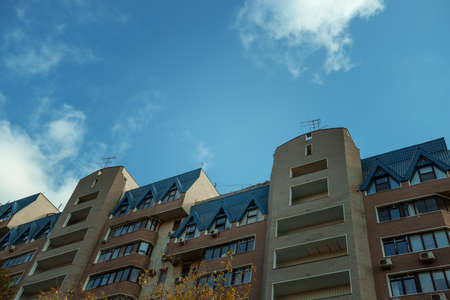 Facade of a high-rise apartment building against a blue sky with fluffy cumulus clouds. typical city...
