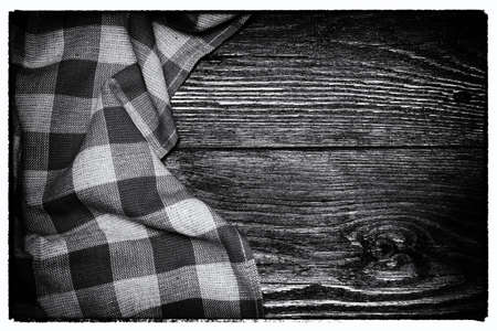 Checkered linen tablecloth on a wooden background. copyspace. Place for food and drink. Picnic and thanksgiving day concept. Black and white vintage image.の写真素材