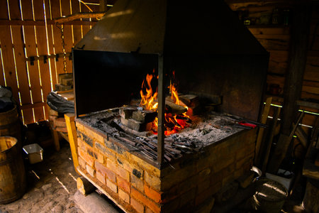 Interior of an old forge. Bright fire burning in the furnace. Forge fire used for creating iron tools in blacksmith's.の写真素材