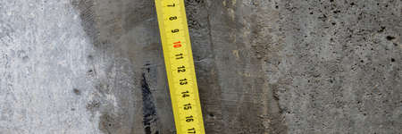 Measuring ruler on a concrete wall texture. The concept of renovation, repair or construction.の写真素材