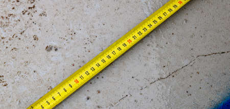 Measuring ruler on a concrete wall texture. The concept of renovation, repair or construction.の写真素材