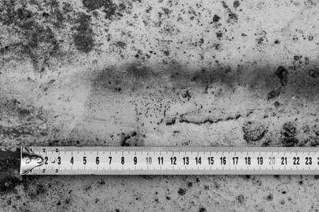 Measuring ruler on a concrete wall texture. The concept of renovation, repair or construction.