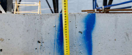 Measuring ruler on a concrete wall texture. The concept of renovation, repair or construction.の写真素材