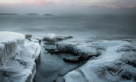 Frozen stones. A stunning seascape amidst the tranquility of a frozen shoreの写真素材