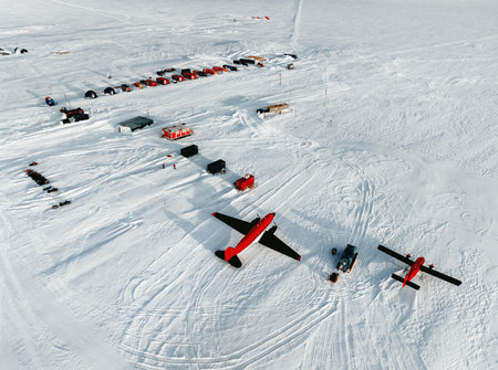 Antarctic base and scientific research station on the Antarctic peninsula. Top view. Red plane sits on the snow. Scientists explore the atmosphere, weather, ice, movement of the earth's crust.の写真素材
