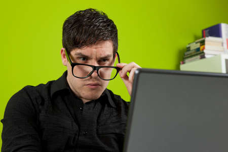 Young man squinting at the laptopの写真素材