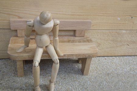 dummy wood man alone on wooden benchの写真素材