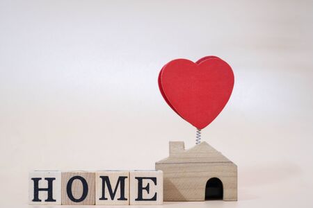 Family Wooden figure with a Wooden house With a Sign HOME Letter Word on Orange Backgroundの写真素材