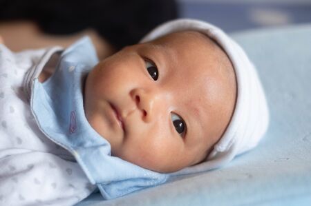 Portrait Photo of happy newborn baby infant with big black eyes lay down on the bedの写真素材