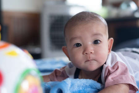 Asian  Adorable infant baby lying on bed with toy Music Ball. Baby Child early development and...