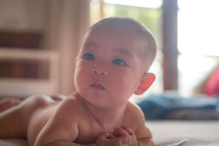Adorable naked curious infant  baby lay on stomach on the bed