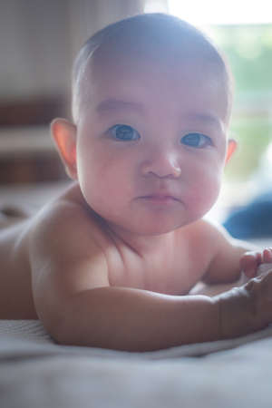 Soft Focus on Adorable naked curious infant  baby lay on the bed after taking a bath