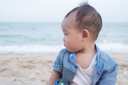 Adorable Cute Asian baby boy playing with beach toys on tropical beachの写真素材