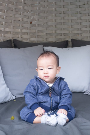Portrait of a little adorable infant baby boy sitting on the Sofa bed