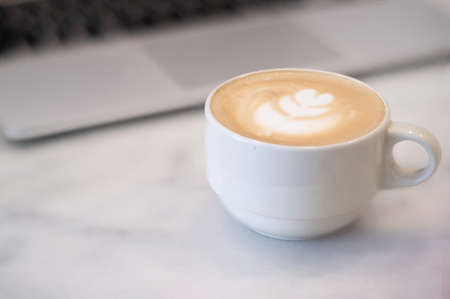 Close-up of Hot coffee latte with latte art milk foam in cup or mug on desk in coffee shop at the cafe business work conceptの写真素材