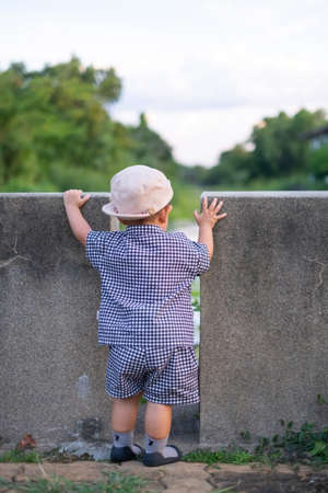 Asian baby boy standing and looking to the small riverの写真素材