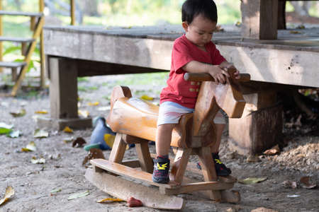 the baby roll on a wooden horse in the summer playgroundの写真素材