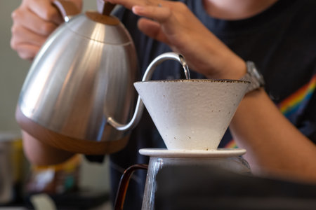 A Barista brew coffee by drip Coffee by Smoothly pouring hot water to ground coffee in white dripper