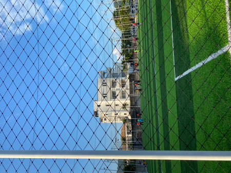 Soccer field and green grass under the net with blue sky.の写真素材