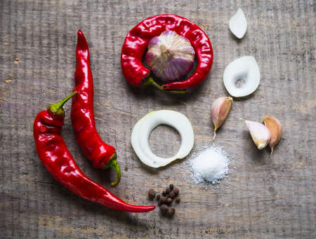 Wooden background with garlic cloves, chili peppers, onion, mix of dry spices and salt.の写真素材