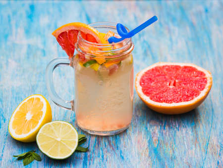 Grapefruit lemonade in pitcher of citrus around on natural wooden table on blue backgroundの写真素材