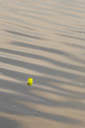 Fishing bobber in water with soft waves.
