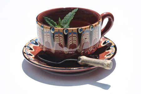 Cup of tea with fresh mint sprig on white background with cast shadow の写真素材