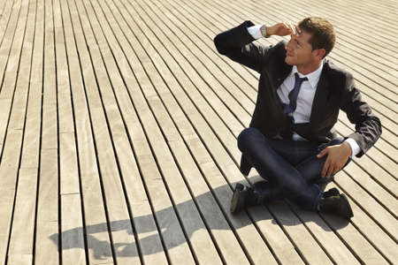 He is sitting on wooden floor and wraps up  his face with the handの写真素材