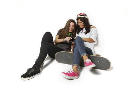 Two young skateboarding looking on phone