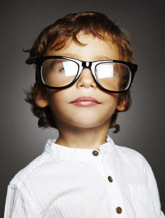 little caucasian boy with black glasses on grey background の写真素材