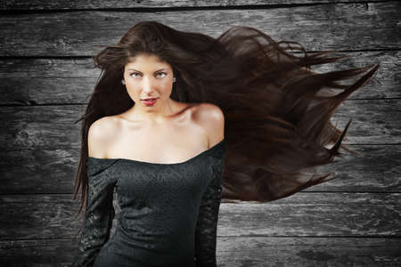 Young brunette woman with long flying hair  grunge background