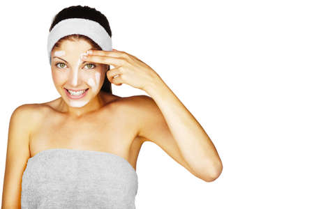 Beautiful young woman applying a creme on her face isolated on white backgroundの写真素材