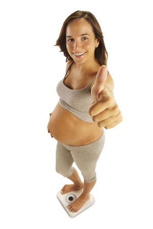 pregnant woman standing on weight scale isolated on whiteの写真素材