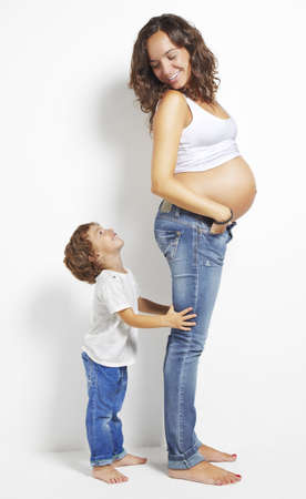 pregnant woman looks a child on a white backgroundの写真素材