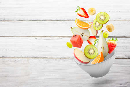 Assorted fresh fruits flying in a bowlの写真素材