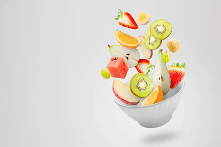 Assorted fresh fruits flying in a bowlの写真素材