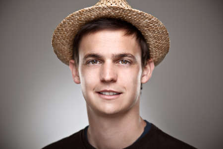 Portrait of a normal young man with straw hat on a grey backgroundの写真素材