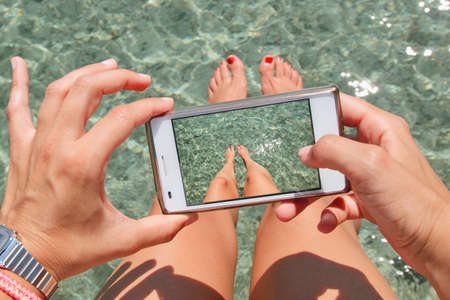 Young woman taking photos of his legs の写真素材