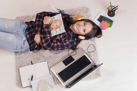 Young creative woman stretched in the floor and listening music の写真素材
