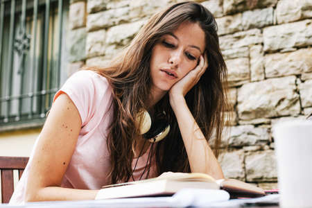 Young woman doing homework on the home garden.の写真素材