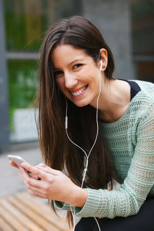 Young woman sitting on a bench in the city.の写真素材