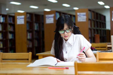Asian girl in uniform studying in libraryの写真素材