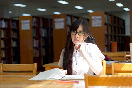 Asian girl in uniform studying in libraryの写真素材
