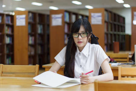 Asian girl in uniform studying in libraryの写真素材