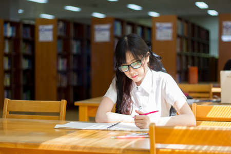 Asian girl in uniform studying in libraryの写真素材