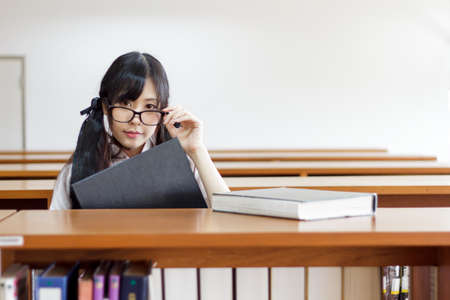 Asian girl in uniform studying in libraryの写真素材