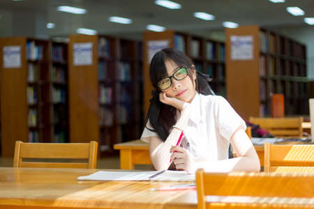 Asian girl in uniform studying in libraryの写真素材